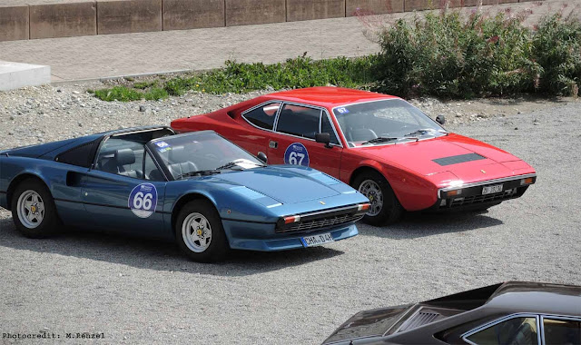 Roter Ferrari 308 GT4 und blauer Ferrari 308 GTS stehen nebeneinander auf Parkplatz vor dem Kulm Country Club, Passione Engadina Event