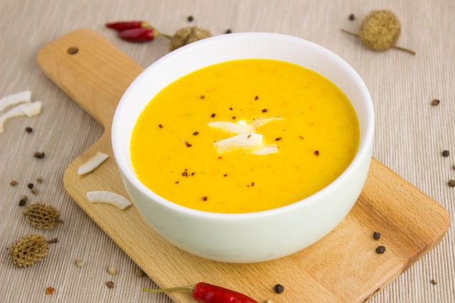Crema de calabaza y coco Bol de crema de calabaza con trozos de coco y pimienta negra