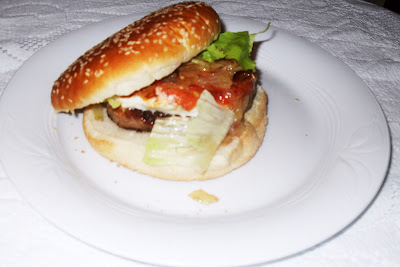 Pan de hamburguesa con la misma y queso rulo de cabra cubierta con lechuga y tomate