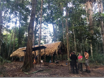 Thatched shelter, fire, four of us eating in a forest clearning
