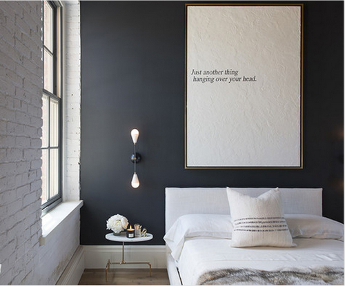 Schwarze Wand, heller Teppich und ein weiches Fell auf dem Bett.