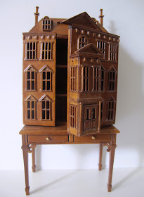 Dolls' house miniature wooden dolls' house mounted on a desk, with the front open to show the shelves inside.