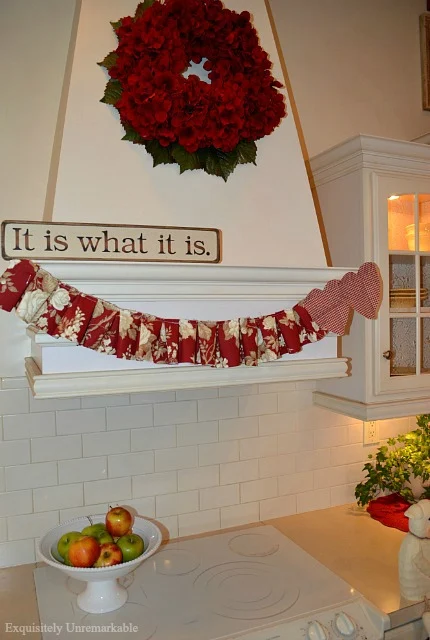 Red wreath and red fabric scrap fabric garland hanging on kitchen hood