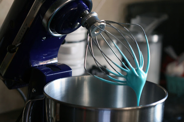 The KitchenAid stand mixer's head is tilted back showing the a solid peak colored meringue mixture.