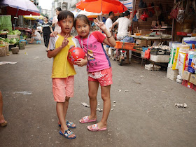 boy and girl with red ball posing for a photo in the middle of Lian'an Street in Zhuhai, China