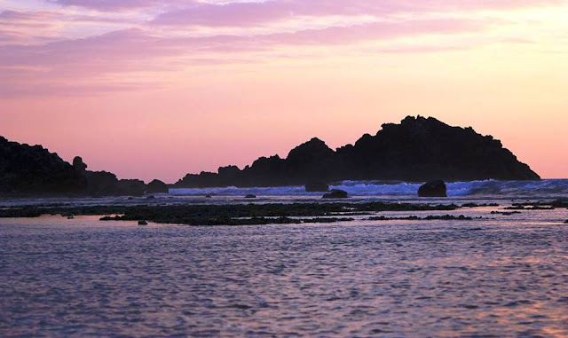 Beautiful view of sunset rays, pristine water and land mass that slap with huge wave