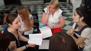 grupo de maestras sentadas en círculo compartiendo la lectura de un texto