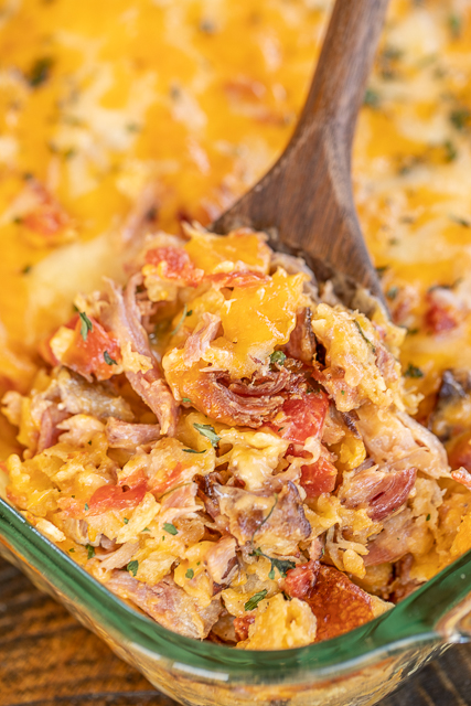 Pulled Pork King Ranch Casserole - a delicious twist on a classic Tex-Mex dish! This isn't fancy. It is just REALLY good!!! Pulled pork, cream of chicken soup, cream of mushroom soup, Cheez Whiz, Rotel tomatoes, hot sauce, Worcestershire sauce, tortilla chips, and shredded cheese. Can make in advance and refrigerate or freeze for later. Great for a potluck and tailgating! I never have any leftovers! #casserole #kingranch #texmex #freezermeal #pulledpork scooping out pulled pork king ranch casserole from baking dish