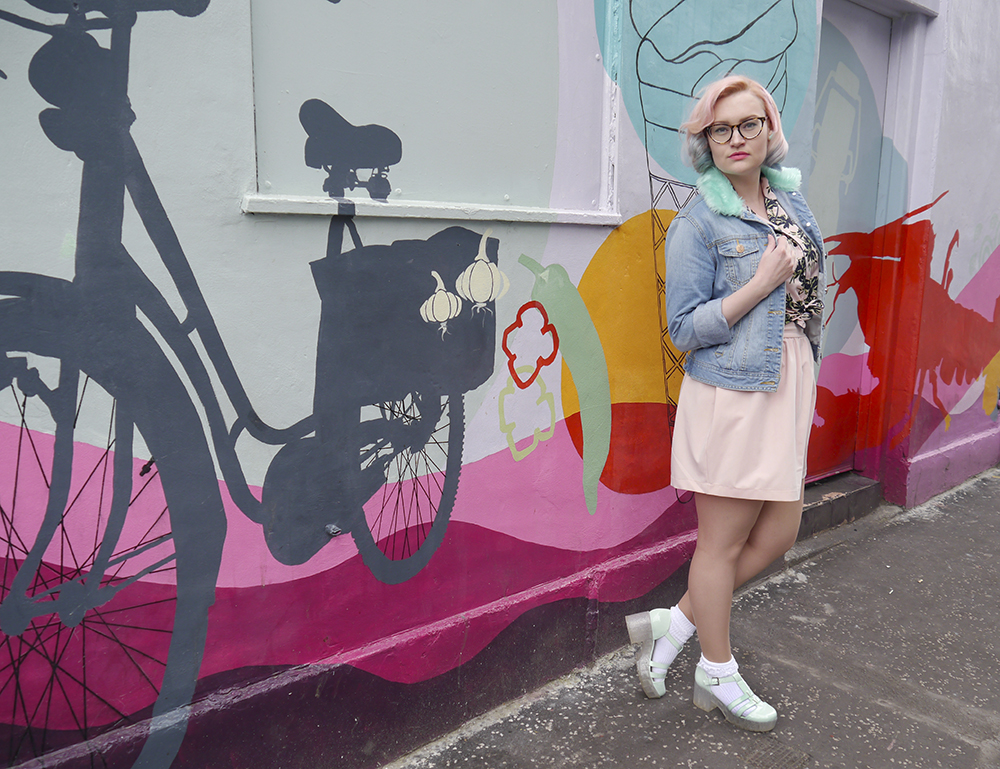 Scottish fashion blogger Kimberley from Wardrobe Converations with candy coloured hair and DIY retro denim jacket standing against grafitti wall in Edinburgh