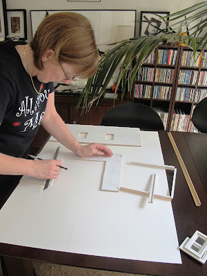 Woman positioning dolls' house kit walls onto of a large piece of mat board.