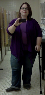 Author dressed in medium blue jeans, light purple t-shirt, darker purple cardigan, using a black cane