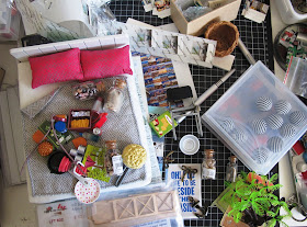 Aerial view of a work table covered with various one-twelfth scale modern miniatures.
