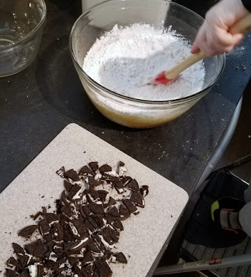 stirring together blondie batter with spatula, cutting board of chopped oreos nearby