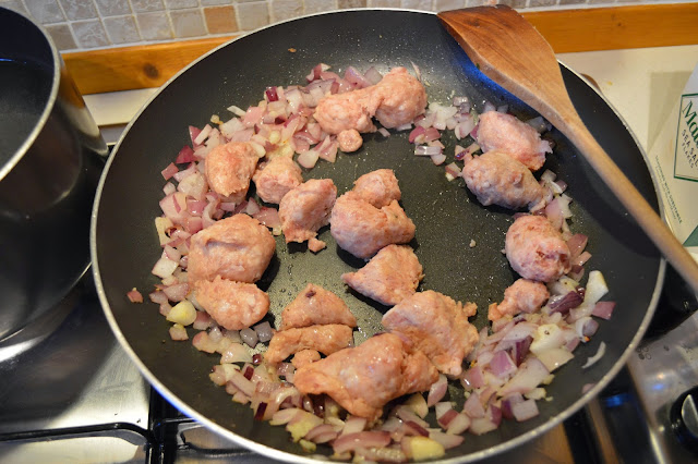 Frying sausages and red onion 