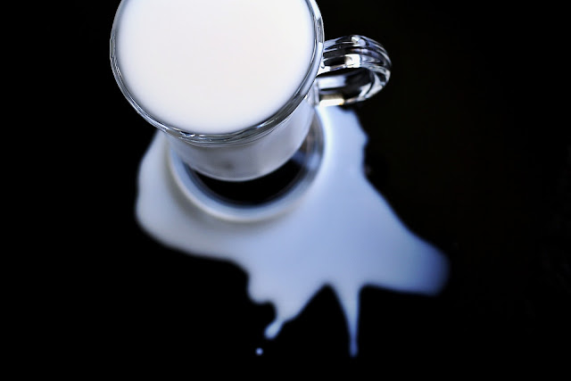 clear glass of milk that has spilled on table