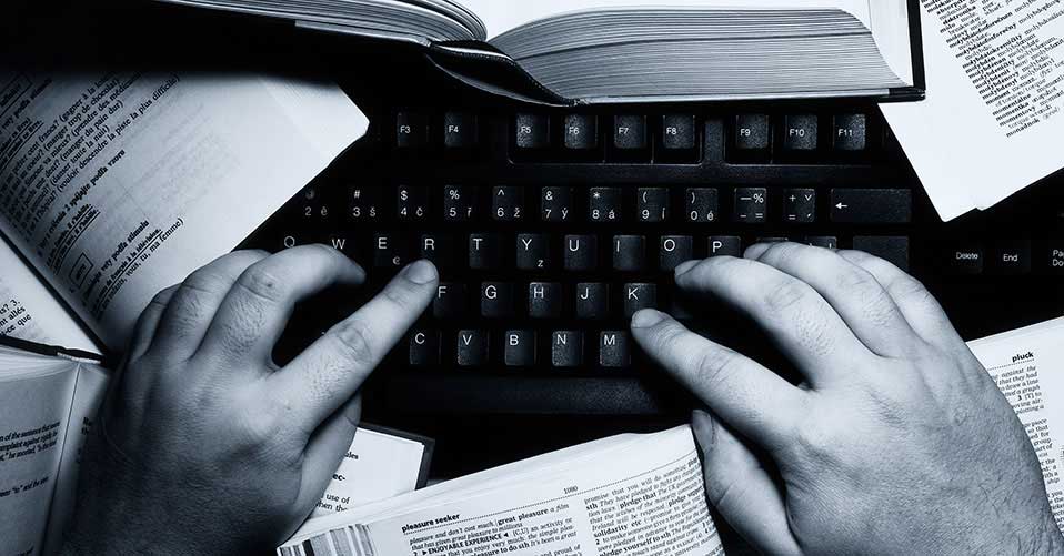 Mãos digitam sobre o teclado de computador