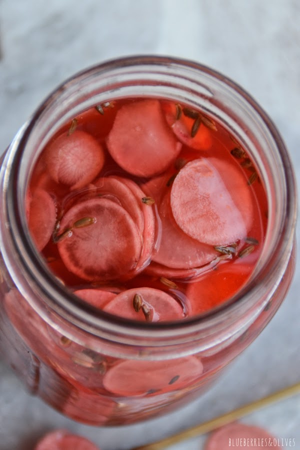 RABANITOS MARINAOS EN TARRO DE CRISTAL SOBRE MÁRMOL BLANCO, FONDO BLANCO 