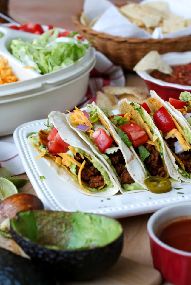 A Guaca-Taco Bar is the ultimate way to feed tacos to a crowd!  Crunchy taco shells are baked in the oven, stuffed with taco meat, and then wrapped with a guacamole smothered flour tortilla to make Guaca-Tacos.  Serve them taco bar-style with all of your favorite classic taco toppings! #GameDayFavorites #OEPGameDay #Sponsored