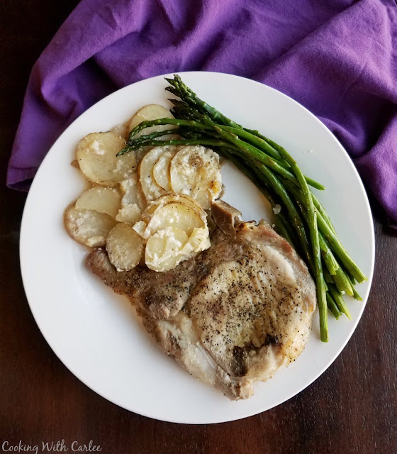 Make your pork chops and scalloped potatoes in the same pan for even bigger flavor and fewer dishes! Maw-Maw definitely had the right idea when she started making this delicious dinner! plate with scalloped potatoes, a pork chop and asparagus on it