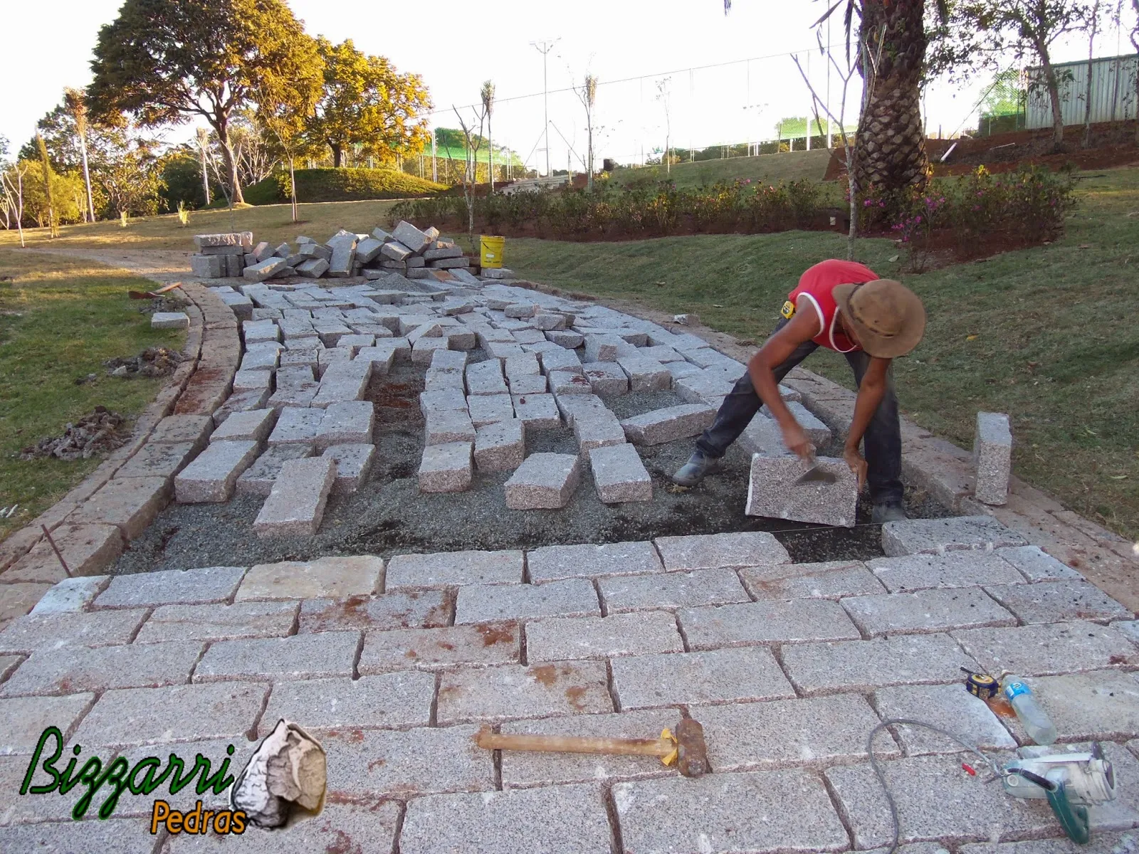 Execução do calçamento de pedra com as guias de pedra na entrada da residência em sítio em Piracaia-SP.