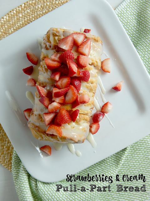Strawberries & Cream Pull-a-Part Bread...a delicious breakfast treat!  Tender, flaky biscuits layered with cream cheese and strawberry jam, then drizzled with thick icing and topped with fresh strawberries!  Ideal for brunches, weekend breakfasts and party desserts.  Sponsored by Kalona SuperNatural. (sweetandsavoryfood.com)