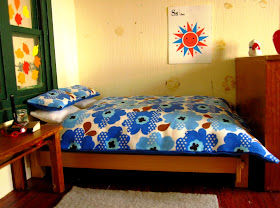 Bed with Marimekko-esque bedding in the corner of a miniature holiday house.