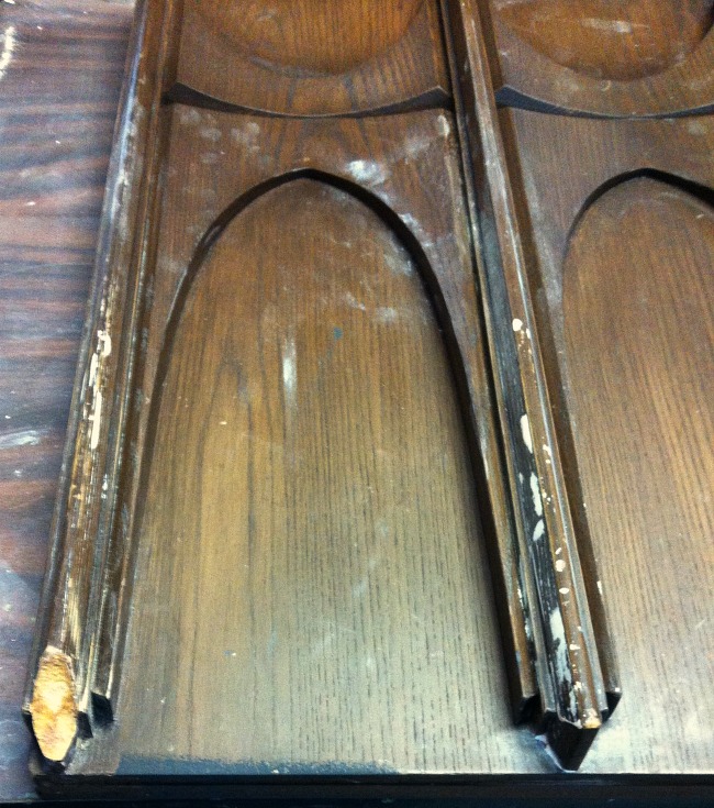 Close up of damaged missing trim on an MCM sewing cabinet door before the furniture repair.