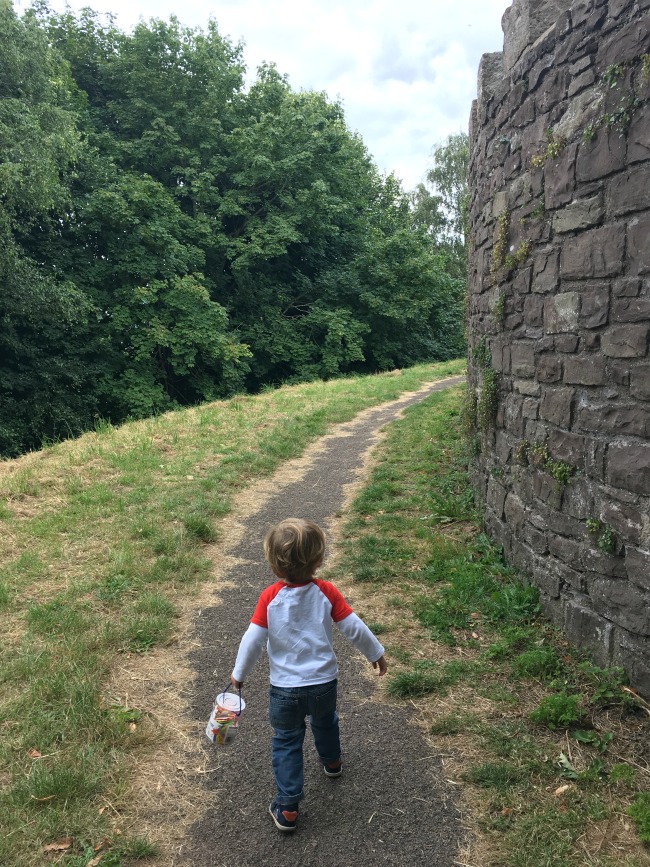 Abergavenny-castle-walls-and-a-toddler-carrying-a-bag-full-of-stickers