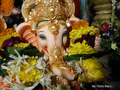 Ganpati idol decorated with flowers in a pandal of a society