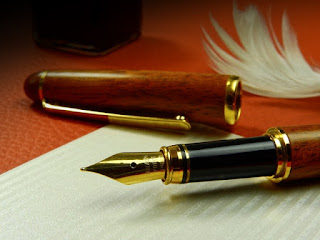 Stock photo of a fountain pen lying uncapped on a blank sheet of white paper, with a leather-covered desktop and a bottle of ink visible in the background.