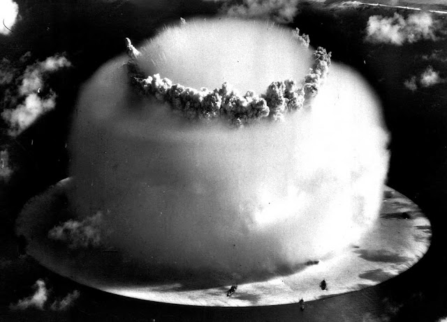 A huge mushroom cloud rises above Bikini Atoll in the Marshall Islands on July 25, 1946, following an atomic test blast, part of the U.S. military's Operation Crossroads. The dark spots in the foreground are ships that were placed near the blast site to test what an atomic bomb would do to a fleet of warships.