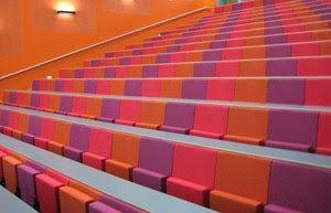Lecture hall chairs in pattern of bright orange, purple and pink colours