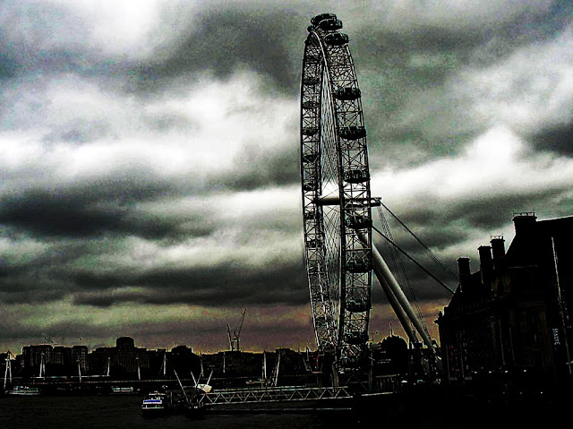 silhouette of the London Eye against a cloudy dark sky