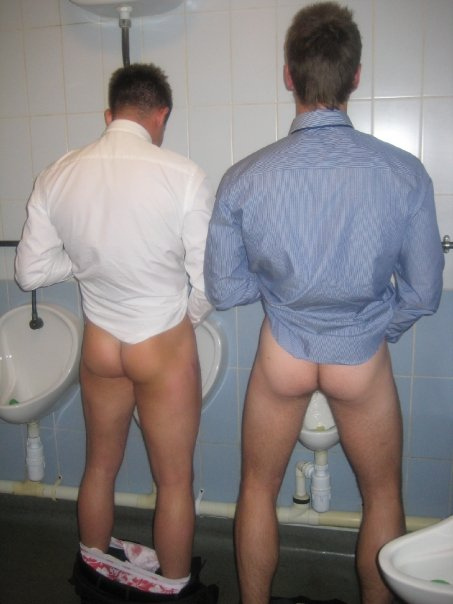 Naked guys pissing at urinal