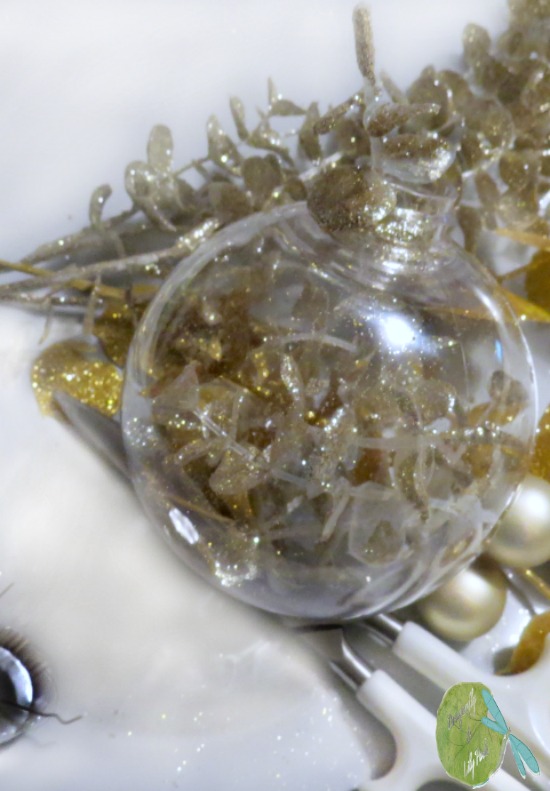 Step one of the ornament tutorial is filling the plastic ball opening with gold glitter stems.