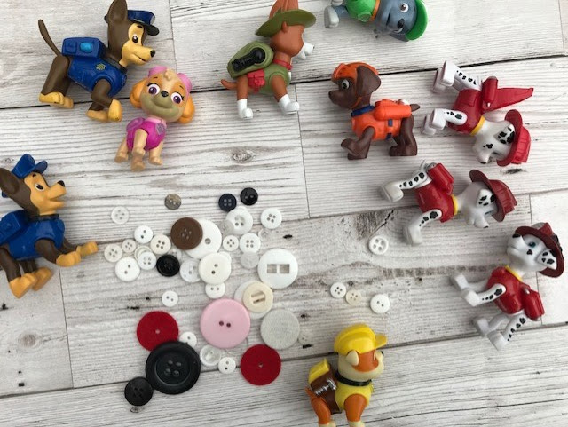 Pile of buttons, surrounded by small Paw Patrol figures