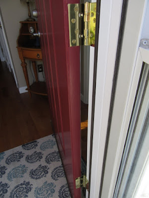 Hinge side of entry door painted the exterior color burgundy.