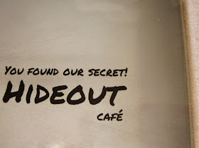 Modern dolls' house miniature window sign which says 'You've found our secret! Hideout cafe"