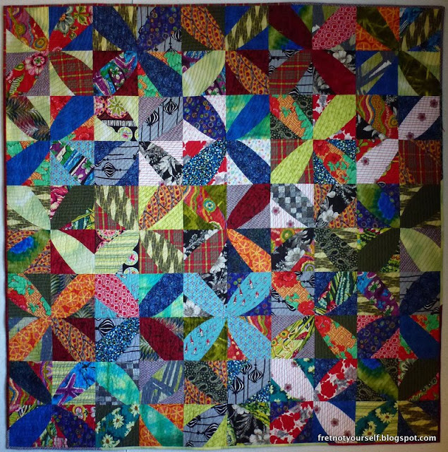 Windmills, an improv quilt based on Cultural Fusion Quilts Strongly patterned fabrics are cut free-form into windmill blade shapes to make the block.