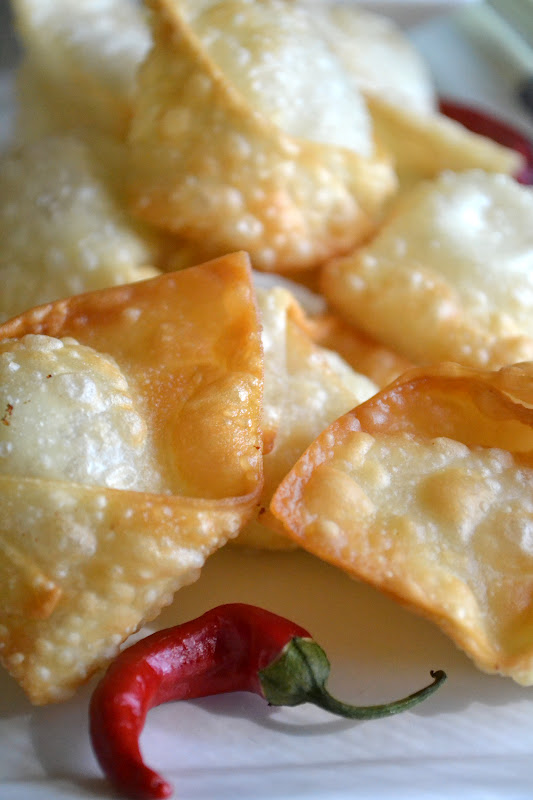 Crispy Goat Cheese Wontons with Chili Dipping Sauce ~ impossibly crunchy little wontons filled with creamy goat cheese ~ this is the appetizer everybody goes wild for! #recipe #easy #chinese #authentic #takeout #creamcheese #appetizer #fried #dumplings Crispy Goat Cheese Wontons on a white plate