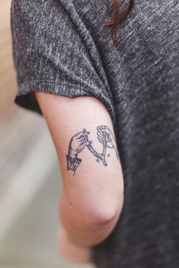 Mujer con tatuaje de horquilla de hueso y dos manos tirando