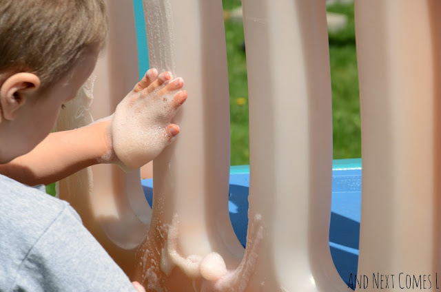 Kid playing with scented colored soap foam outdoors