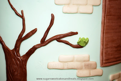 Attaching clusters of fondant leaves to tree along side of cake.