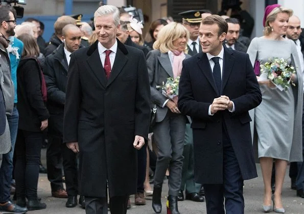 President Emmanuel Macron. First Lady Brigitte Macron is waring grey suit, and Queen Mathilde wore Merino wool cape dress