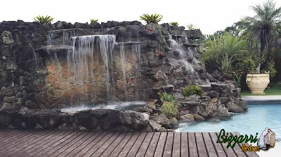 Execução da cascata de pedra na piscina com execução da hidromassagem com um lago de pedra ornamental e a execução do deck de madeira.