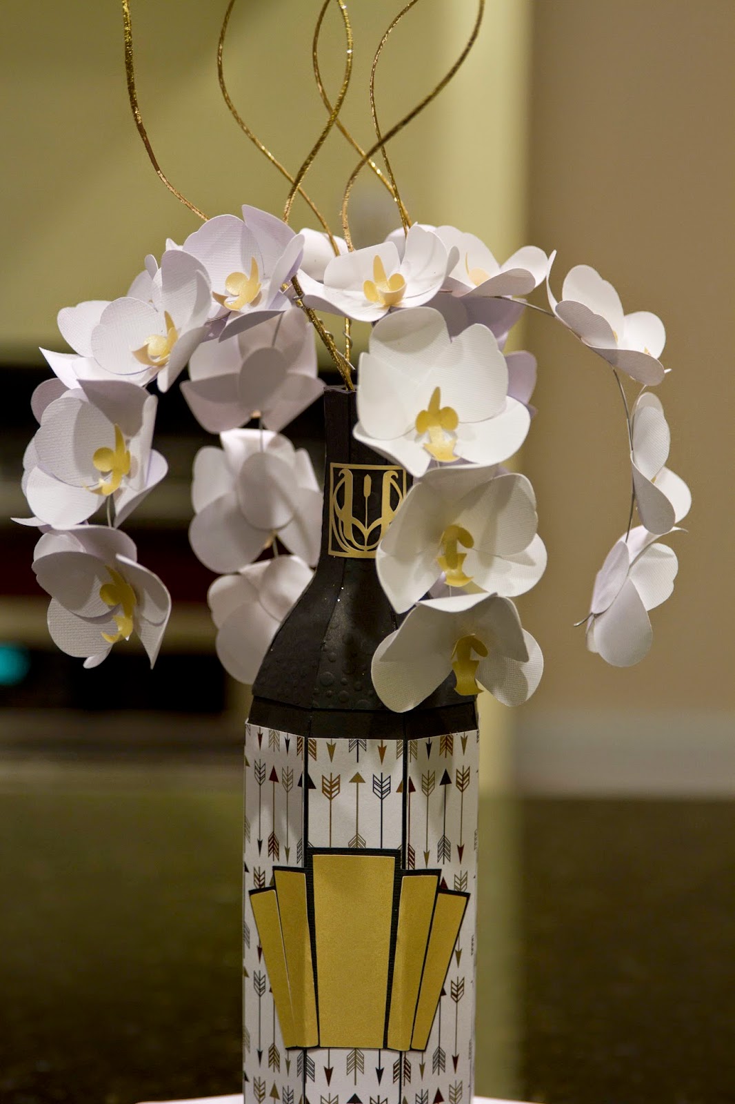 paper champagne bottle with orchids casading out of the top standing on top of large dice