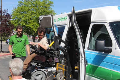A young man in a wheelchair enters a van via a lift