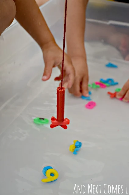 Child fishing for numbers in a water math activity