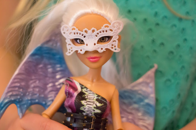A close up of the Camryn Project Mc2 doll showing her lace style white mask, dragon wings and belt