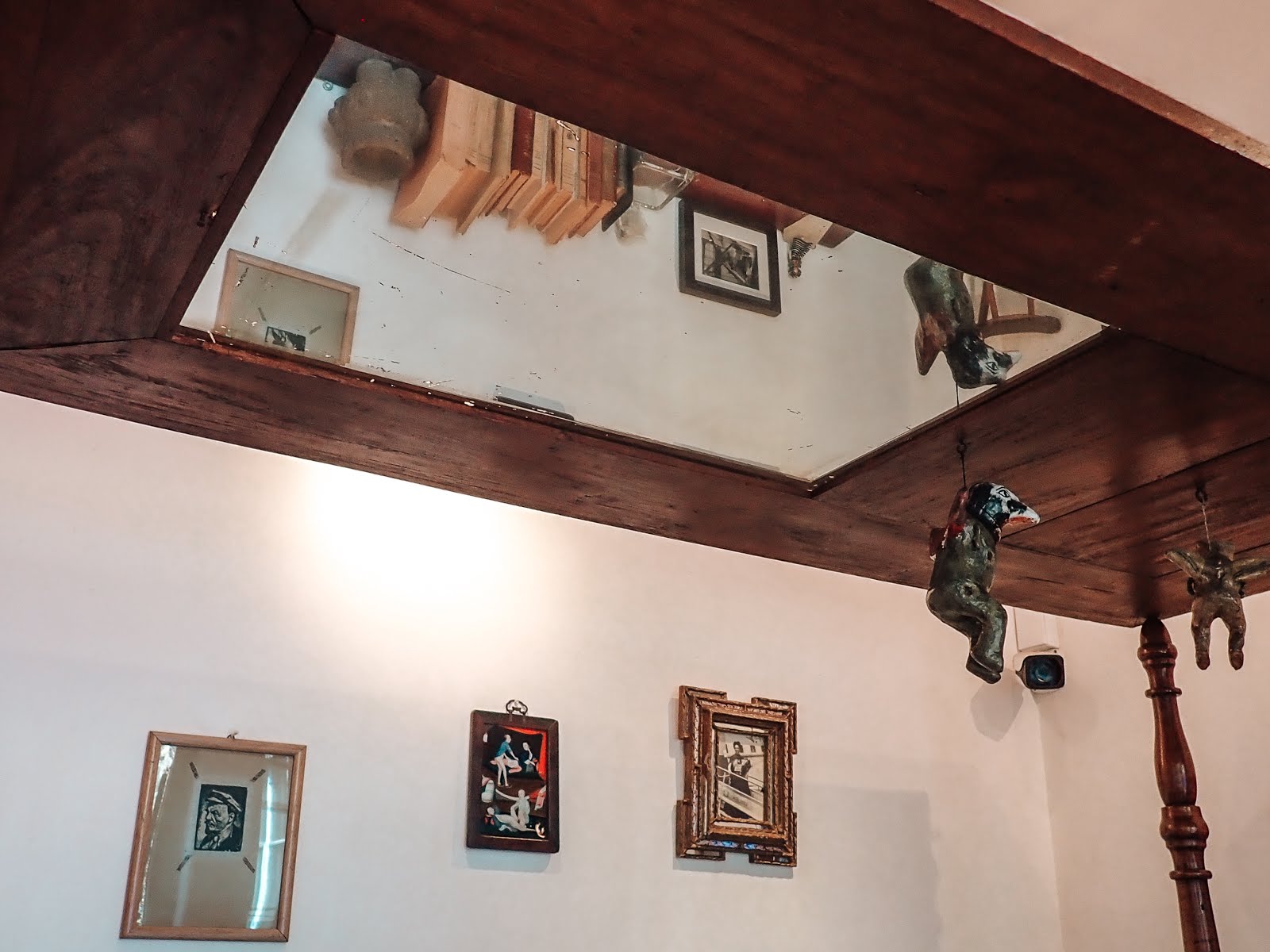 le lit en bois de frida khalo dans la casa azul de mexico city sur lequel est disposé un miroir et une figurine mexicaine noire rouge qui est suspendue